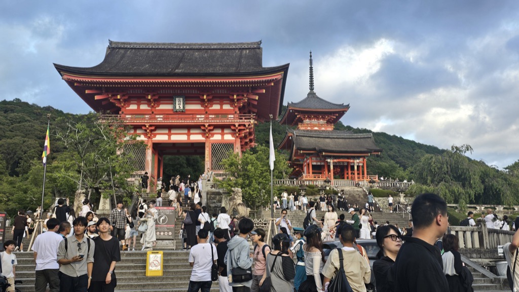 Kiyomizu-dera vermillion Niomon gate and three-story pagoda under an evening sky with pilgrims