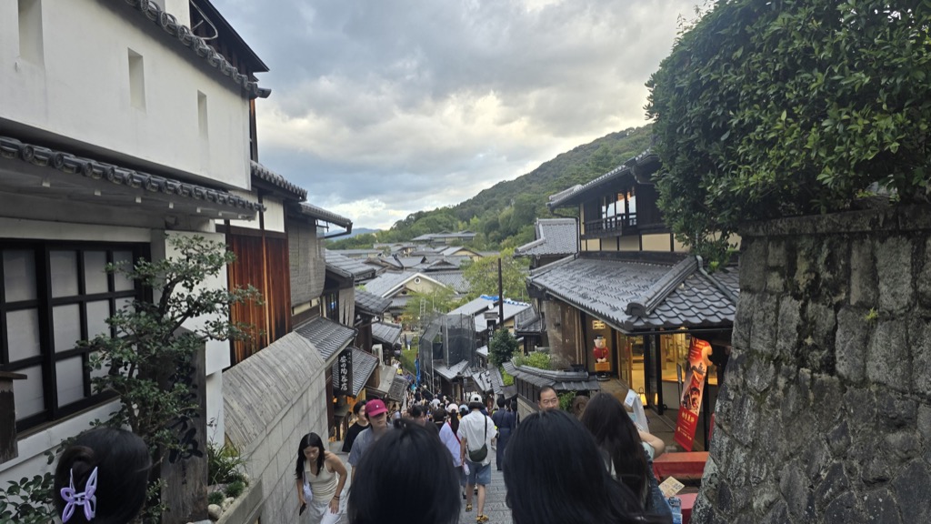 Sannenzaka slope traditional Kyoto stone-paved street with wooden machiya shops and travelers at dusk