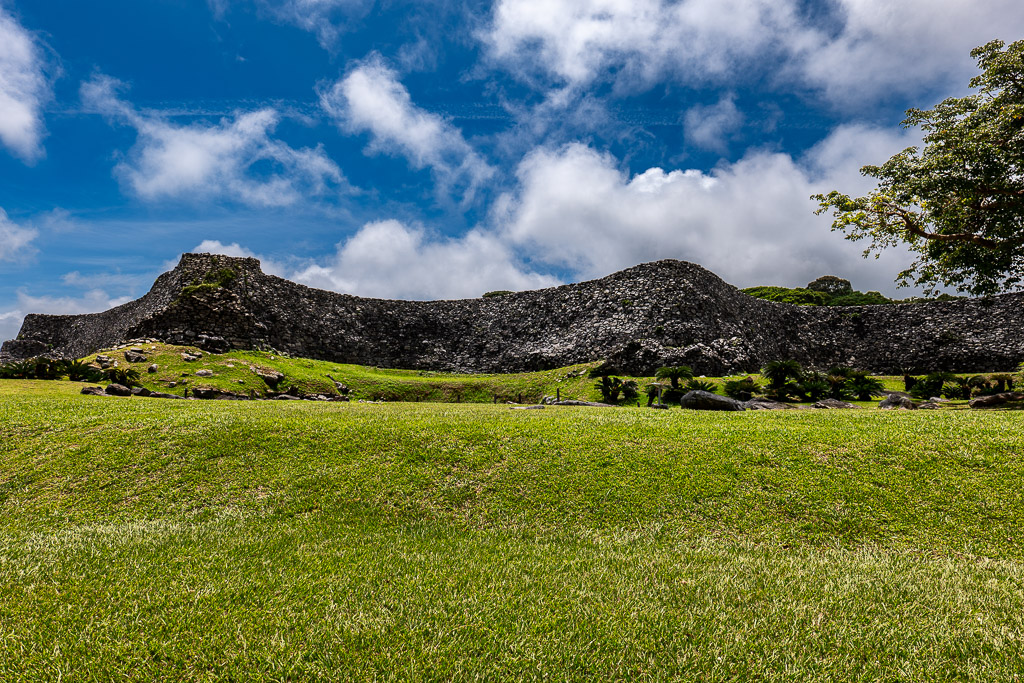 Dramatic Ryukyu castle stone wall against blue sky viewed from the base looking up