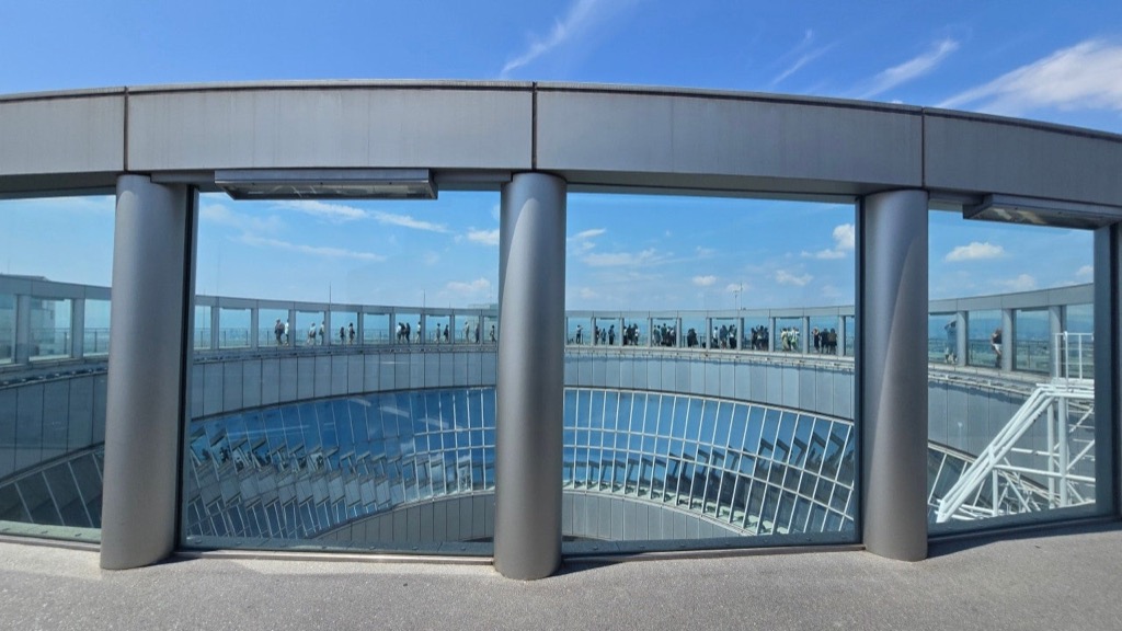 Visitors spread along the open-air observatory deck of the Umeda Sky Building under a deep blue mid-September sky