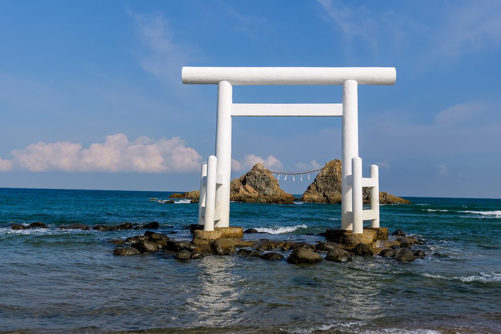 The white torii on the beach with the two rocks silhouetted against the setting sun over the Genkai Sea