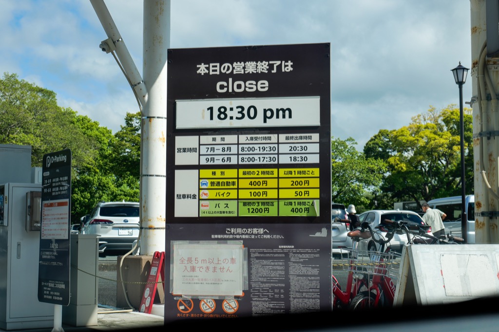 Kumamoto Castle parking rates and opening hours sign at the entrance