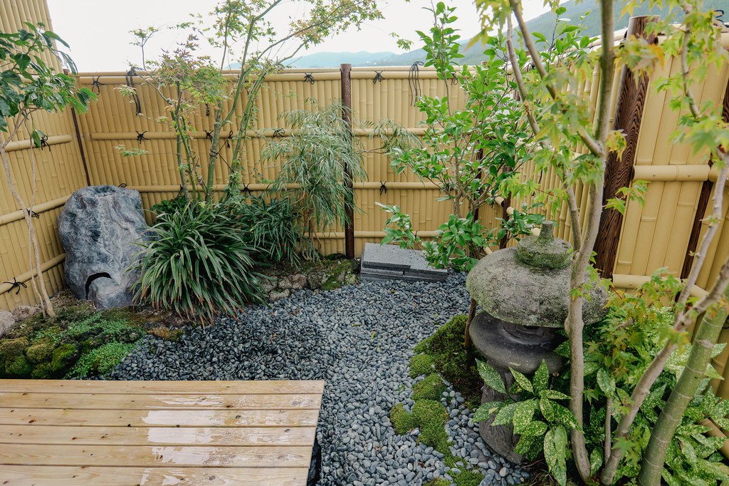 Small Japanese garden inside a Yufuin ryokan with bamboo fencing and stone lanterns